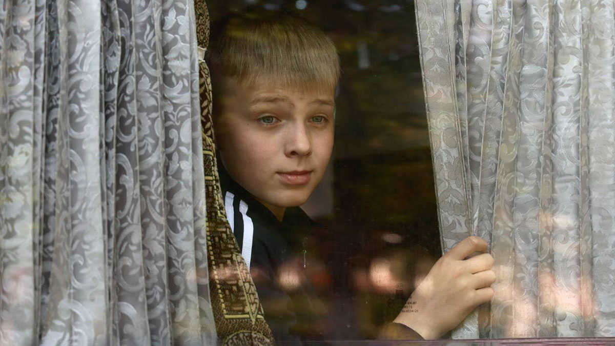 Ребенок смотрит из окна эвакуационного автобуса в Белгородской области.